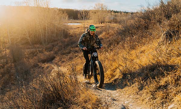 A man wearing a helmet is riding a Brawn long-range e-bike on a hill