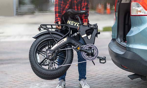 A man is placing Tyson Fold Up eBike on the trunk